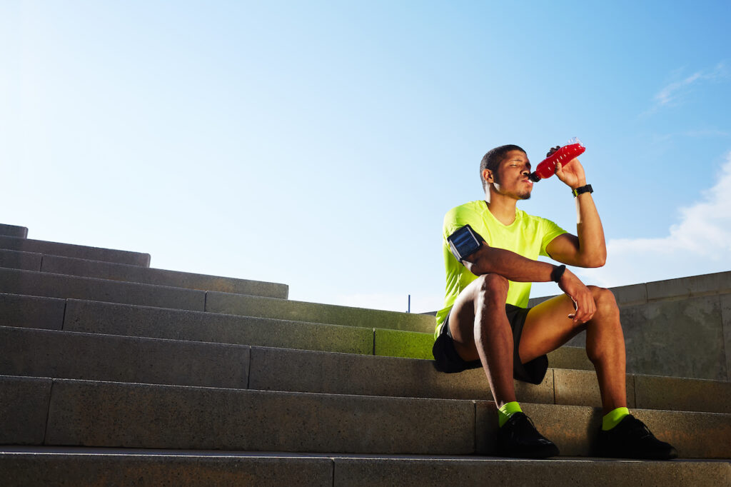 Running in the heat thirsty man drinks energy drink