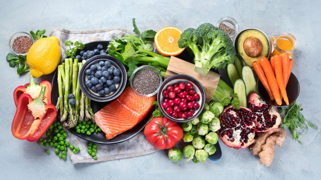 a selection of healthy foods for runners such as carrots, broccoli, salmon, berries, oranges, asparagus, lemon, avocado